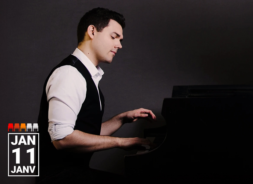 A man in a white dress shirt and black vest is playing a piano. He has short, dark hair and is seated at the piano with a focused expression. The background is dark, and the date "JAN 11" is prominently displayed in the bottom left corner of the image.